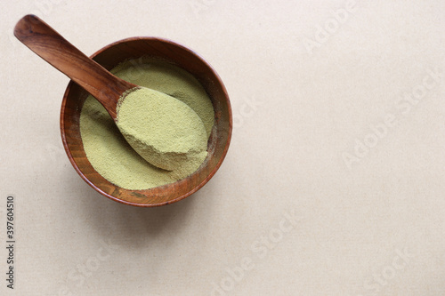Powder matcha green tea in a bowl on wooden background