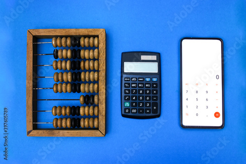 Technological progress concept. Calculation, counting technologies development. Old wooden abacuses, calculator and smartphone with calculator on light blue background. Top view. 