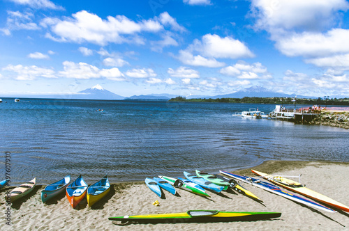 Large beautiful blue lake with boats and the Osorno volcano blurred in the background.