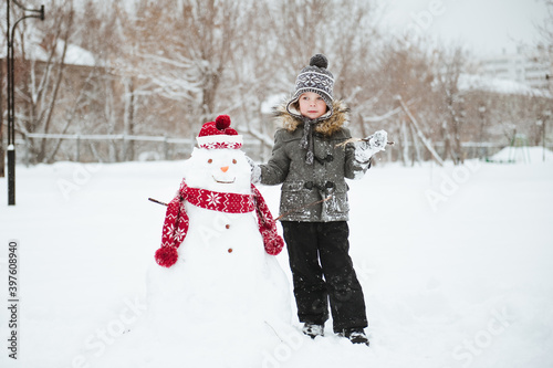 Cute little boy made snowman in winter Park.