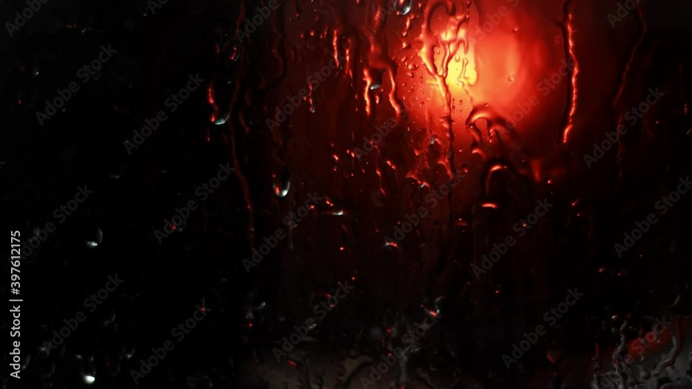 Background with raindrops on a black background for overlay to create mood. Light water on window with red light outside. Wet noir background
