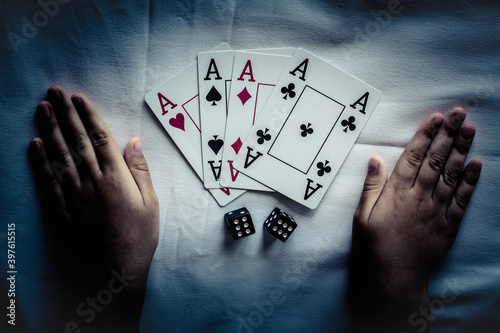 On the table is a deck of playing cards and two dice. Near two children's hands.
