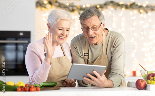 Senior Couple Using Tablet Making Video Call In Kitchen