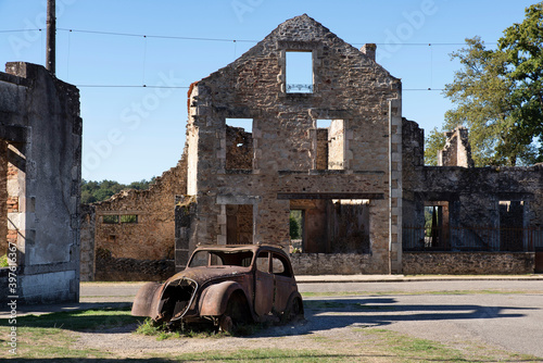 Ruin of the village of Oradour sur Glane in France with a rusty old car, remnant of an old war massacre photo