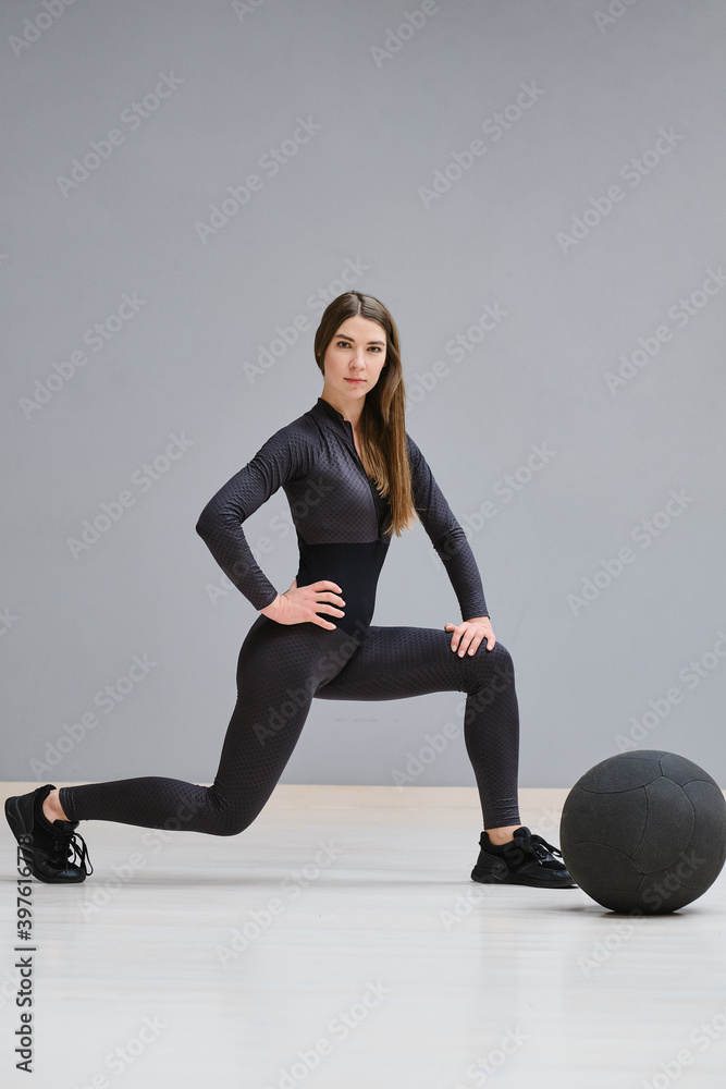 Beautiful young girl in sportswear is engaged in training with a big gymnastic ball. The girl does sports training, sports. Fitness woman