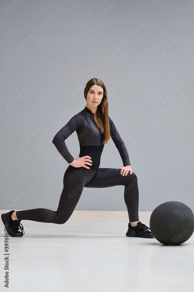 Obraz premium Beautiful young girl in sportswear is engaged in training with a big gymnastic ball. The girl does sports training, sports. Fitness woman
