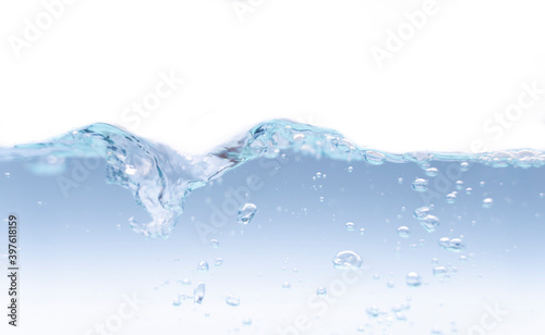 A photograph of a moving water wave with a small amount of bubbles. Where the water is blue and the backdrop is white