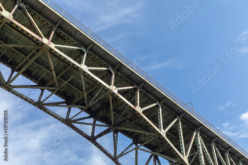View from underneath an old arch highway bridge silhouetted against a blue sky, creative copy space, horizontal aspect