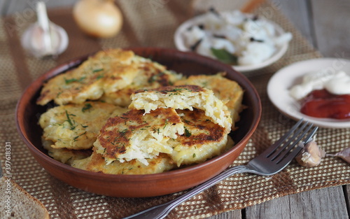Home cooking potato pancakes or potato pancakes.The national dish of Belarus, Ukraine and Russia. On a wooden background, potato pancakes surrounded by sauce, salted fish and spices.