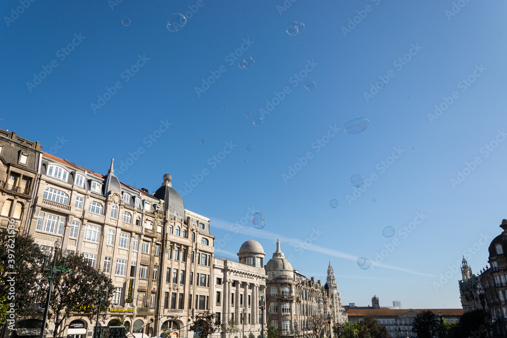 Fototapeta premium Porto, Portugal - 08/28/2019: Big soap bubbles and Porto city in the background. Aliados Avenue.