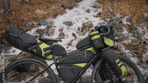 The mixed terrain cycle touring bike with bikepacking. The travel journey with light bicycle bags designed or modified for cycling. The trip on bike, outdoor in magical autumn forest, river stream. photo