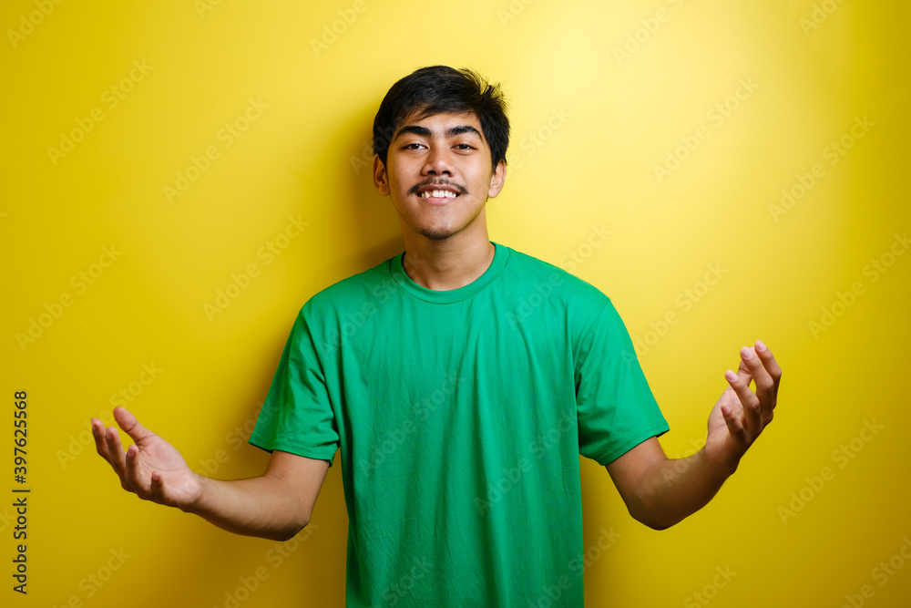 Young Asian Man in Green T-shirt Smiling and Shows Asian Greeting Gesture