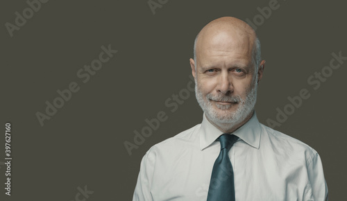Confident middle-aged businessman smiling and looking at camera