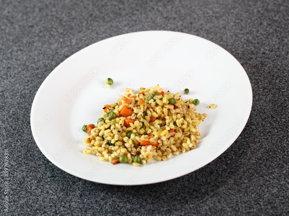 Cooked pearl barley with carrot and green peas on plate Cooked pearl barley with carrot and green peas on plate