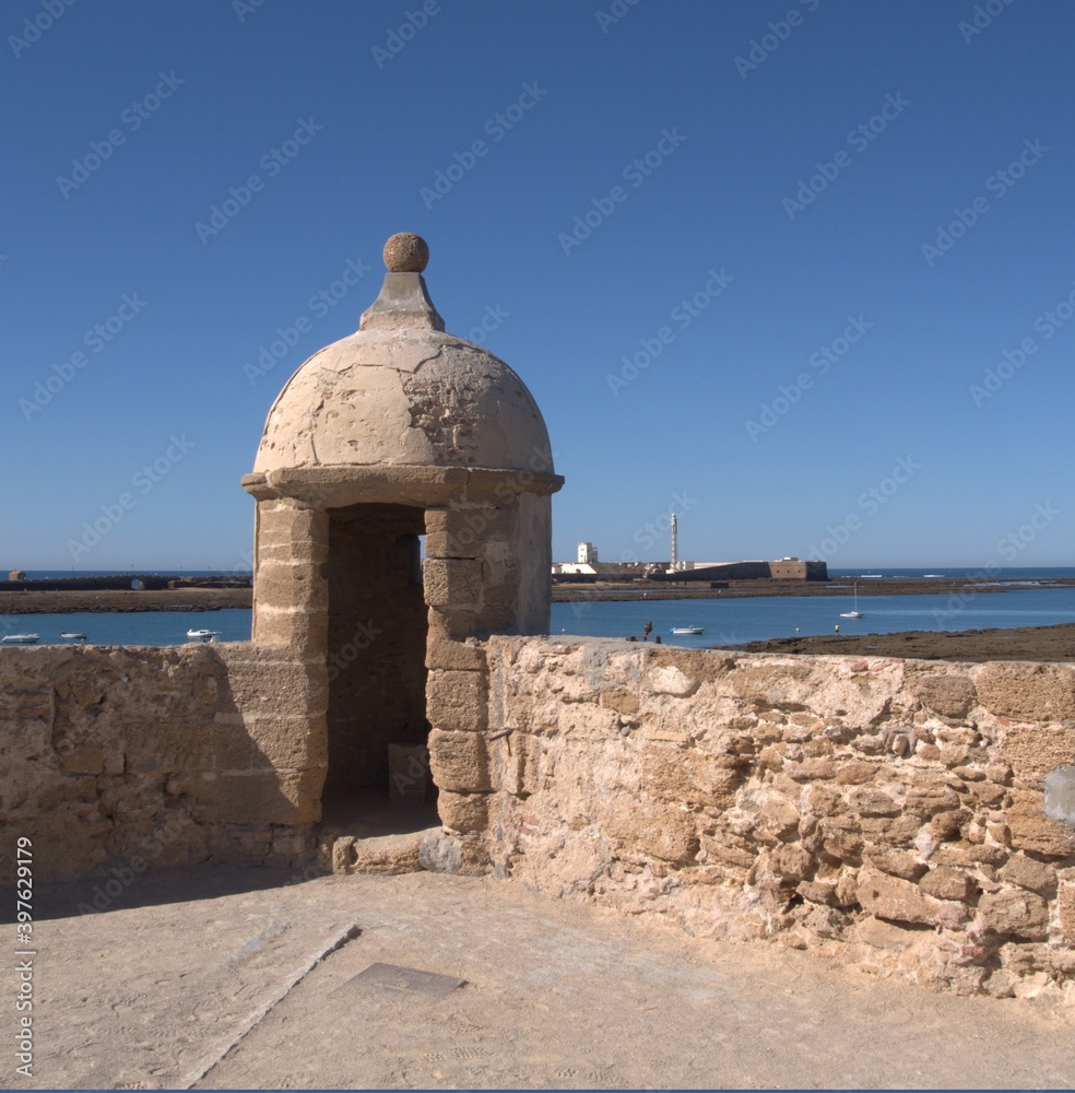 Fototapeta premium Sentry box in the Castle of Santa Catalina, Cadiz, in the background the Castle of San Sebastian and its lighthouse