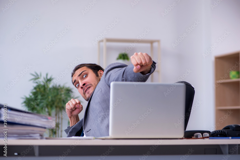 Young male employee unhappy with excessive work in the office Young male employee unhappy with excessive work in the office