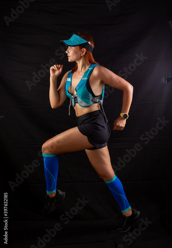 girl in blue jogging uniform runs in the studio on a black background