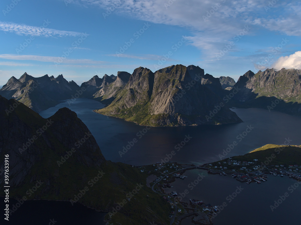 Stunning aerial panorama view of fishing village Reine, calm fjords and the majestic mountain range of Moskenesøya island, Lofoten in northern Norway in the evening light in late summer.