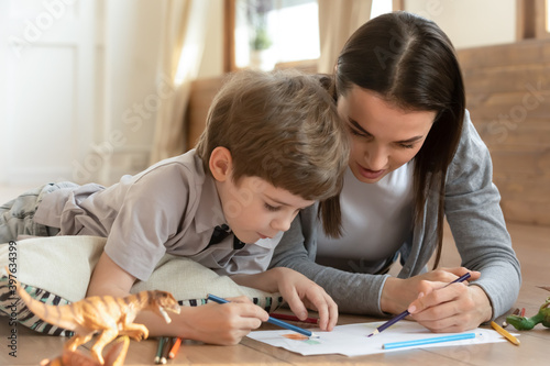 Photos Caring young Caucasian mother and small son drawing painting in album at home together