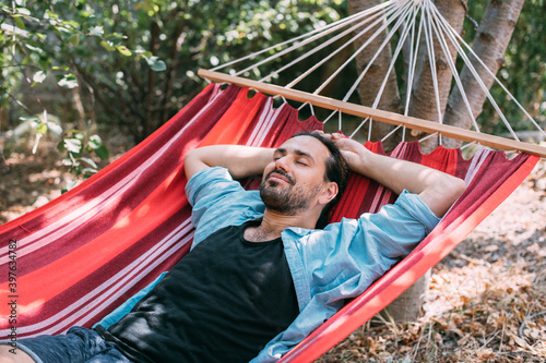 Young man is resting in a hammock in the garden