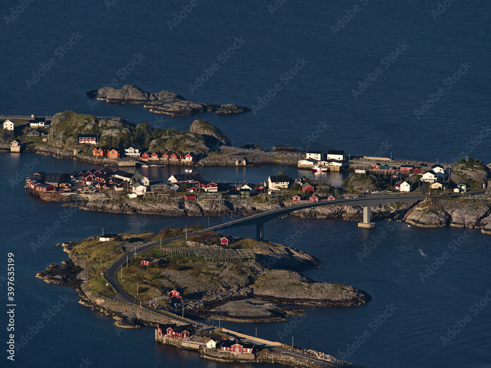Stunning aerial view of small fishing village Hamnøy located on islands on coast of Moskenesøya island, Lofoten, Norway with bridge, traditional red colored wooden rorbu houses and stockfish rackss.