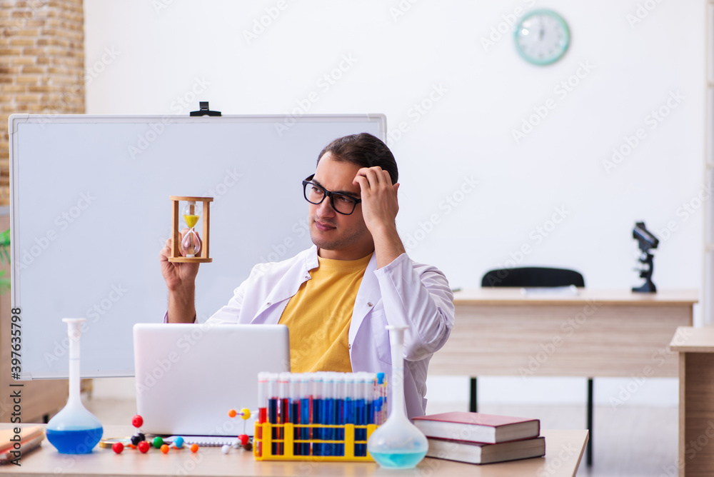 Young male chemist in time management concept Young male chemist in time management concept