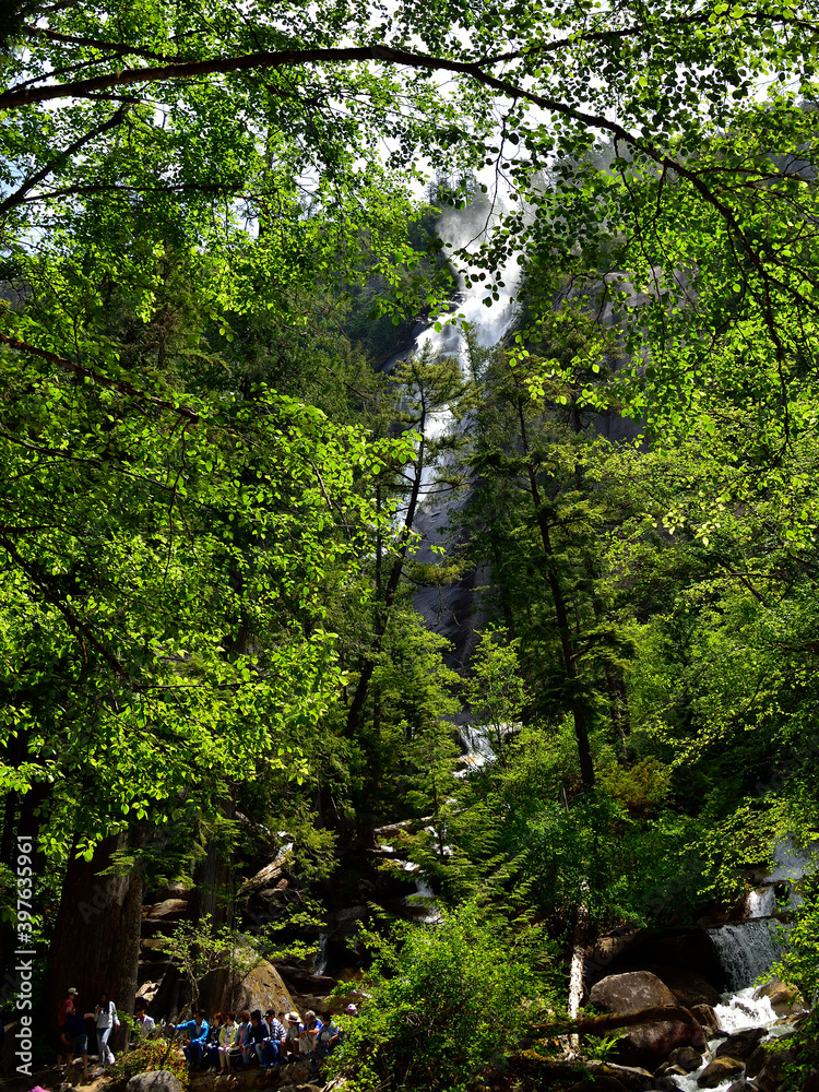 Fototapeta premium SQUAMISH, BC, CANADA, JUNE 02, 2019: People resting and sitting on stones at the foot of Shannon Falls, Squamish, British Columbia