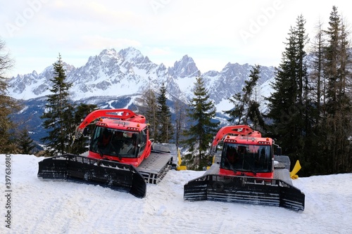 Two standing snow groomers next to ski slope on Monte Elmo/Helm. Croda Rossa peak in background. Dolomites, Italy, Puster Valley/Alta Pusteria, South Tyrol.