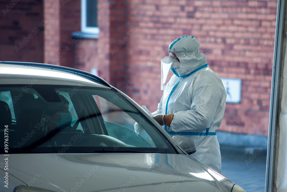 Covid-19 testing. A doctor in a protective suit taking mouth swab from a person to test for possible coronavirus infection Covid-19 testing. A doctor in a protective suit taking mouth swab from a person to test for possible coronavirus infection