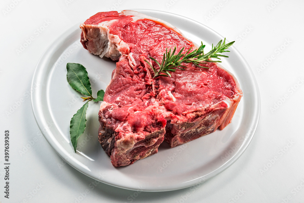 Raw T-bone steak with bay leaf and rosemary