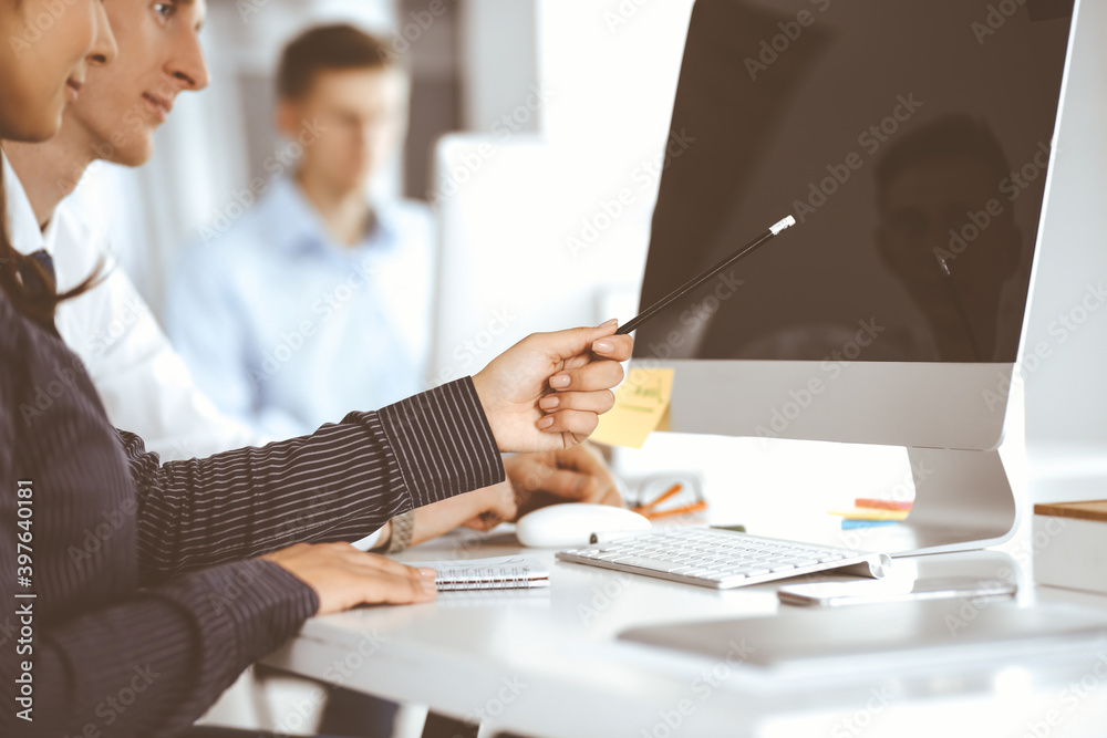 Business woman and man are discussing questions while using computer and blocknote in modern office, close-up. Teamwork in business