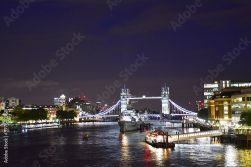 View of the River Thames at night with the illuminated London Bridge and HMS Belfast.