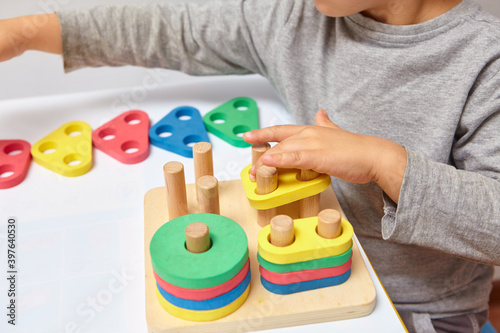 The child collects a sorter. Educational logic toys for kid's. Children's hands close-up. Montessori Games for Child Development. Multicolored logic sorter on white background.