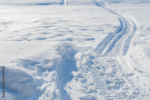 Snowmobile tracks in deep snow. Twisting traces of a snowmobile crossing snow covered field © Koirill
