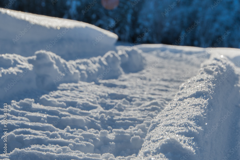 Snowmobile tracks in deep snow. Twisting traces of a snowmobile crossing snow covered field