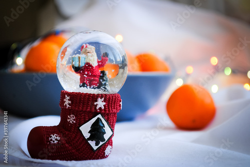 Snow globe and tangerines on the table. Christmas mood.