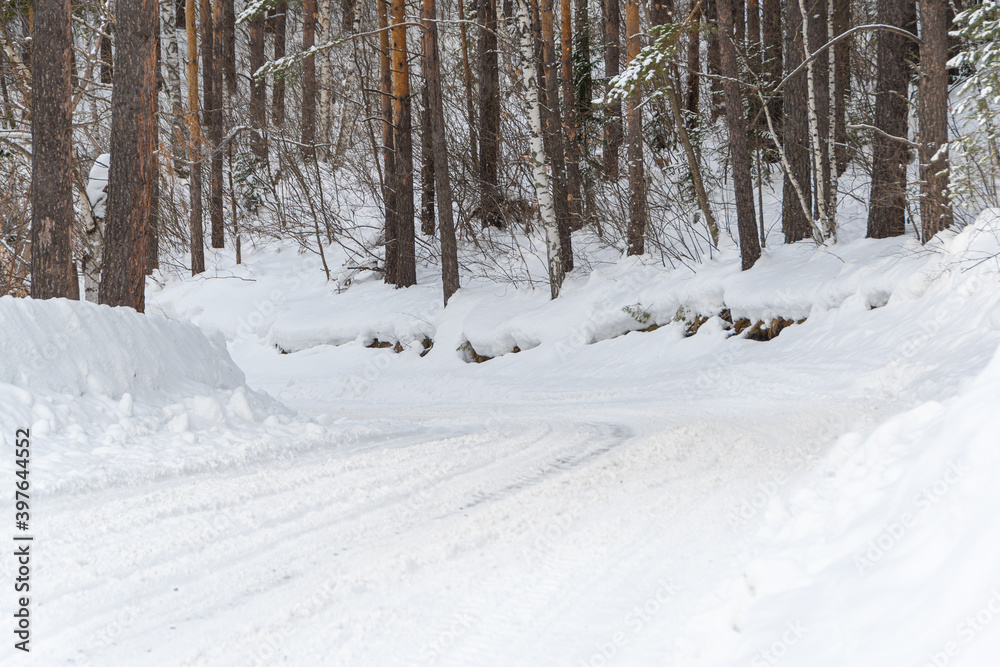 Snow road in winter pine forest. Ice and snowstorm on a country road. Clearing the road from snowdrifts. Snow road in winter pine forest. Ice and snowstorm on a country road. Clearing the road from snowdrifts.