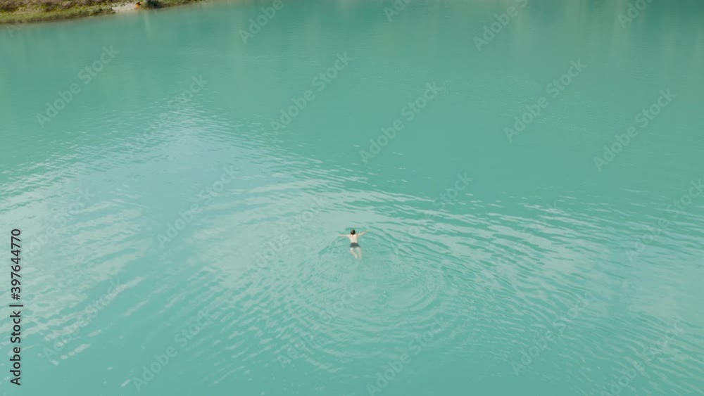 One guy swimming alone in the middle of a green lake on a summer day at Lake Tenno, Italy One guy swimming alone in the middle of a green lake on a summer day at Lake Tenno, Italy