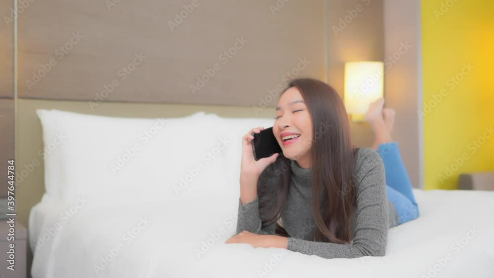 Attractive young woman talking to somebody on the mobile phone while lying on her white bed with her bare feet up in the air. Attractive young woman talking to somebody on the mobile phone while lying on her white bed with her bare feet up in the air.