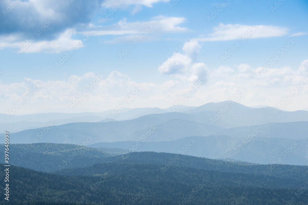 Thick clouds over mountain range, hills in blue haze