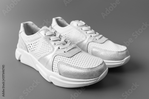 Two white women's leather sneakers on a gray background