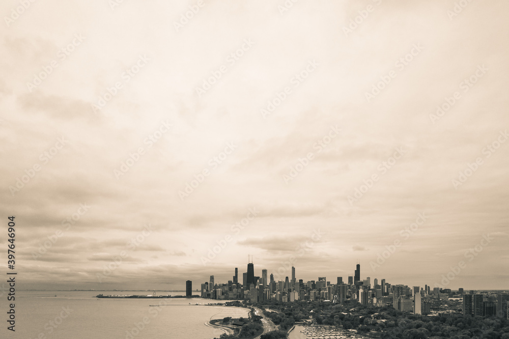 Black and white aerial skyline view of city of Chicago from the north side along the shoreline of Lake Michigan with Lake Shore drive and Diversey Harbor below and cloudy sky above with copy space.