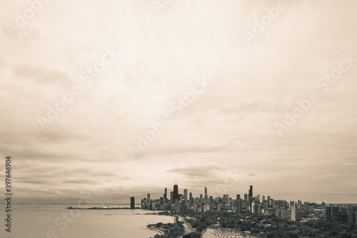 Black and white aerial skyline view of city of Chicago from the north side along the shoreline of Lake Michigan with Lake Shore drive and Diversey Harbor below and cloudy sky above with copy space.
