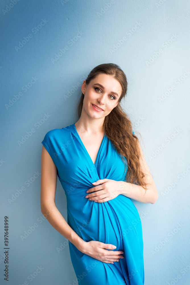 portrait of a pregnant woman in a blue dress on a blue background portrait of a pregnant woman in a blue dress on a blue background
