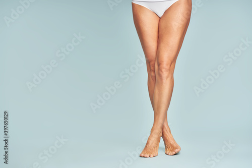 Perfect hair removal. Cropped shot of a woman with perfectly shaven legs standing over blue background