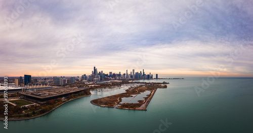 Wide angle Chicago city skyline aerial panorama with Northerly Island and Lake Michigan in foreground and highrise skyscraper buildings along the horizon with a beautiful orange and blue sunset sky.