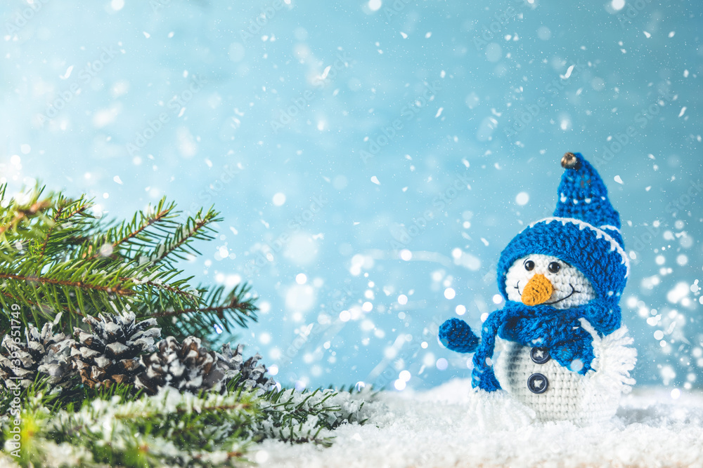 Obraz premium Christmas or winter composition. Little knitted snowmans on soft snow on blue background. Christmas, winter, new year concept.