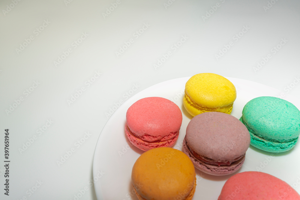 multicolored macaroons on a white plate on a gray background multicolored macaroons on a white plate on a gray background