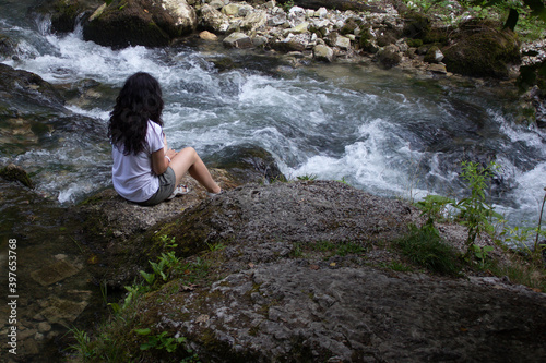 A girl sitting on the river bank in silence