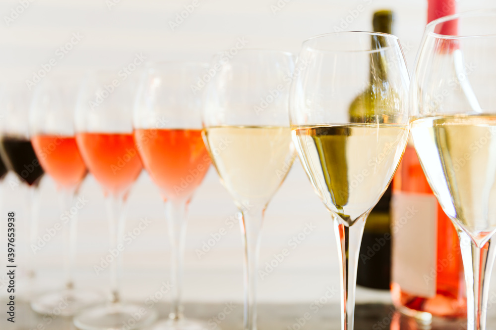 Wine tasting set in the light airy environment. Custom wine tasting concept. Glasses of wine and bottles on the glass table and light background.